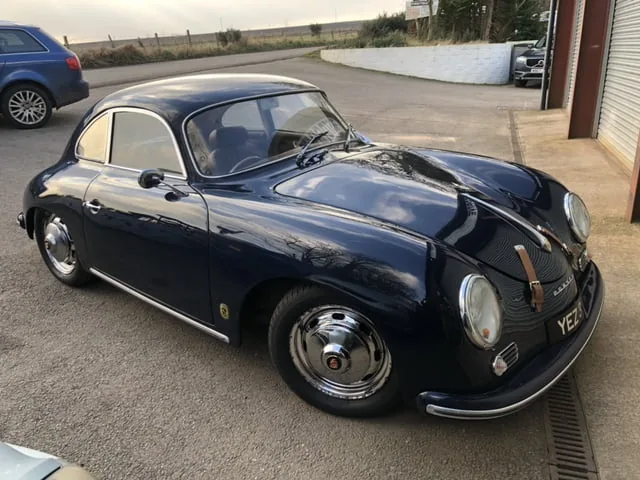 A dark blue Porsche 356 outside the workshop